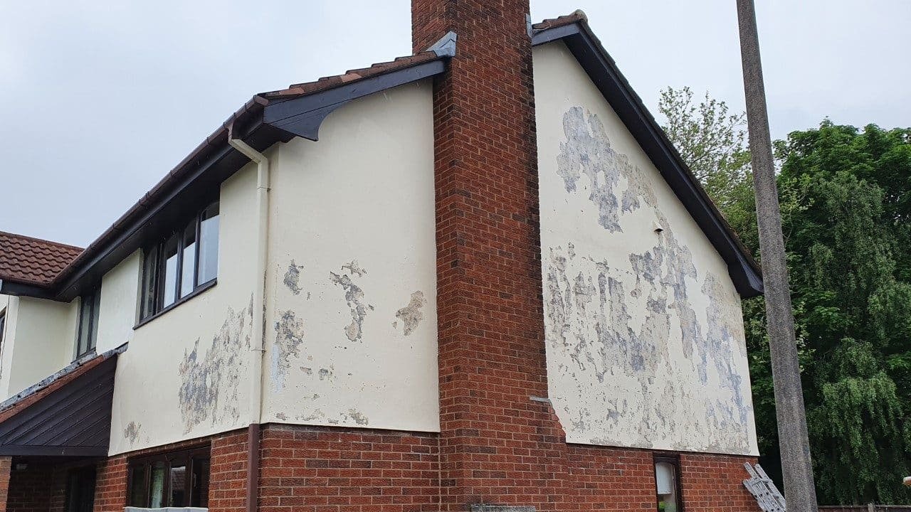 Exterior view of a house showing peeling paint on the side walls, a brick chimney, and a nearby power pole.