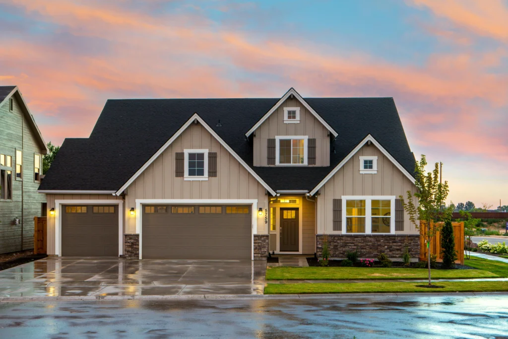 Modern suburban home with a stone accent, double garage, and lush landscaping, set against a colorful sunset sky.